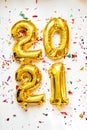 Gold foil balloons numeral 2021 with colorful confetti on white background. Happy New year 2021 celebration