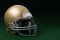 Gold football helmet on dark green background