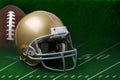 Gold football helmet and football on green field