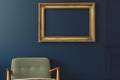gold frame on a dark blue wall, midcentury armchair below