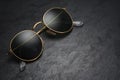 Gold frame round black sunglasses on black slate background Royalty Free Stock Photo