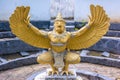 Gold Garuda bird sculpture in a pond background