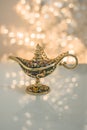 A gold genie Aladdin lamp on blurred shiny with glitter sparkle light white background