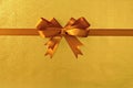 Gold gift bow ribbon, shiny metallic foil paper background, straight horizontal