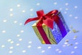 Gold gift box with red ribbon floating on blue background with shining stars and blurry lights. Minimal concept for christmas Royalty Free Stock Photo