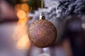 Gold glitter Christmas tree glass ball bauble decoration, golden bokeh, snowy background Royalty Free Stock Photo