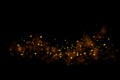 Gold glitter particles lights trail and bokeh on a black background. Christmas abstract sparkle texture