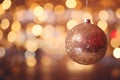 Gold glittery shimmering Christmas ornament hanging in front of blurred background of bokeh lights. Sparkling