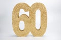 A gold glittery sign that says the number 60 on a white background