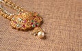 Gold Guttapusalu Necklace with gemstones a traditional Indian wedding jewelry on wooden textured background