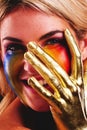 Gold hand, woman and beauty portrait with color paint cosmetics on skin and face in studio. Female model person with a Royalty Free Stock Photo