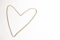 A gold heart is made of chain, symbol of love on a white textural background at the left side