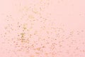 Gold holographic glitter on pink background, abstract texture.