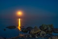 Gold hour over the wild rocky beach coastline and the sea. Moon and rocks at night wide angle view Royalty Free Stock Photo