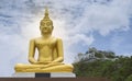 Gold image of Buddha with blue sky and cloud, mountain with temple on hilltop, light effect added in back of image of buddha Royalty Free Stock Photo