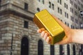 gold ingot in hand on background Federal Reserve Bank of New York. The building hosts a vault containing the world's largest Royalty Free Stock Photo