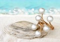 Gold Jewellery ring with pearls on sand beach background, soft f