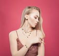 Gold jewelry model. Blonde woman with fashion golden chain earrings, bracelet and necklaces on colorful pink background Royalty Free Stock Photo