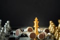 Gold king chess stands on chessboard surrounding with opponents on dark background