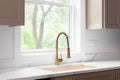 A gold kitchen faucet detail with brown cabinets and marble countertop.