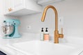 A gold kitchen faucet detail on a white countertop.