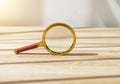 Gold magnifying lens on wooden desk. Magnifier on wood table