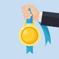 Gold medal with blue ribbon for first place in hand. Trophy, winner award isolated on background. Golden badge icon. Sport, Royalty Free Stock Photo