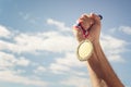 Gold medal held in hand raised against sky background Royalty Free Stock Photo