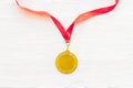 Gold medal with red ribbon - winner, success concept - on white wooden background top view