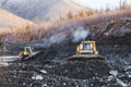 Gold mining industry. Bulldozers rake gold-bearing mountain soil into a heap