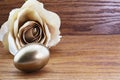 Gold nest egg with beige rose shows successful investing