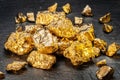 Gold nuggets on black stone background top view. Imitation of gold nuggets Royalty Free Stock Photo