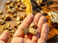 Gold nuggets on a brass plate and on palm. Imitation gold nuggets Royalty Free Stock Photo