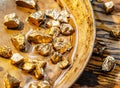 Gold nuggets on a brass plate on a wooden tabletop. Imitation gold nuggets Royalty Free Stock Photo