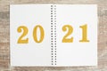 Gold number 2021 on open notebook on wooden background