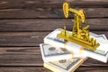 Gold oil pump on wads of money on a wooden background. fuel industry