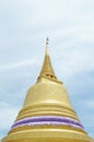 gold pagoda with blue sky and white cloud background. The little turquoise buddha is in front of the gold pagoda