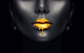 Gold paint drips from the lips, golden liquid drops on beautiful model girl`s mouth, creative abstract dark black skin makeup Royalty Free Stock Photo