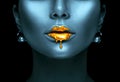 Gold paint drips from the lips, golden liquid drops on beautiful model girl`s mouth, creative abstract dark blue skin makeup Royalty Free Stock Photo