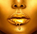 Gold paint drips from the lips, golden liquid drops on beautiful model girl`s mouth, creative abstract makeup Royalty Free Stock Photo