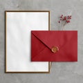 A gold picture frame stands beside a red envelope with a wax seal on a textured gray surface Royalty Free Stock Photo