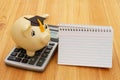 Gold piggy bank with a grad cap, notebook, and calculator on wood desk Royalty Free Stock Photo