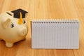 Gold piggy bank with a grad cap on wood desk Royalty Free Stock Photo