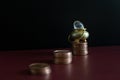 A gold pot with a gemstone on top of a stack of money coins Royalty Free Stock Photo