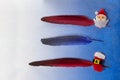 Gold, red, blue, silver feathers with pin with santa claus and a boot on a blue background. For list, write text, planning Royalty Free Stock Photo