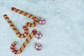 Gold and red candy canes with glitter Christmas baubles on the snow. Royalty Free Stock Photo