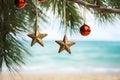 Gold and red Christmas ornaments on tropical beach. Christmas toys handing on a palm tree against exotic tropic sand beach. Happy Royalty Free Stock Photo