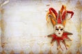 Gold and red elegant traditional venetian jester mask over distressed old white wooden background