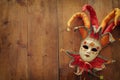 Gold and red elegant traditional Venetian jester mask over old wooden background