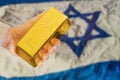 gold reserve of the Israel concept. Gold bar in hand on israeli flag background